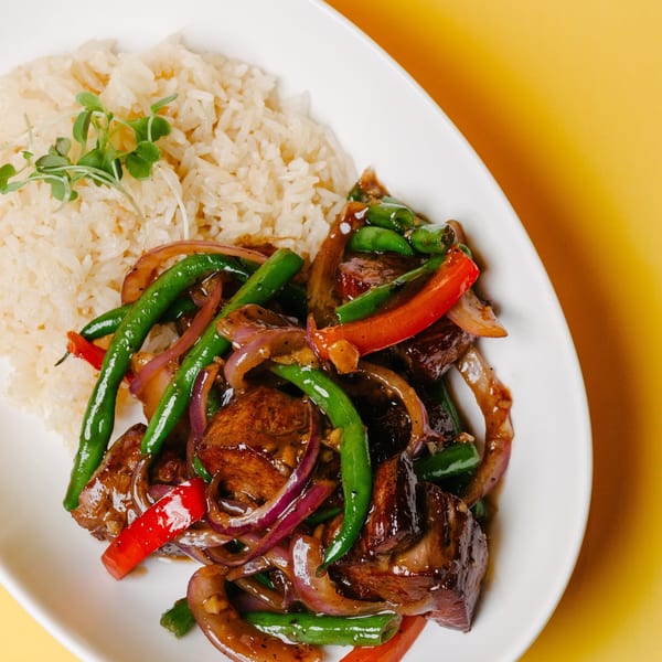 Asian-fusion beef stir-fry with green beans, red peppers, and onions, served with rice.